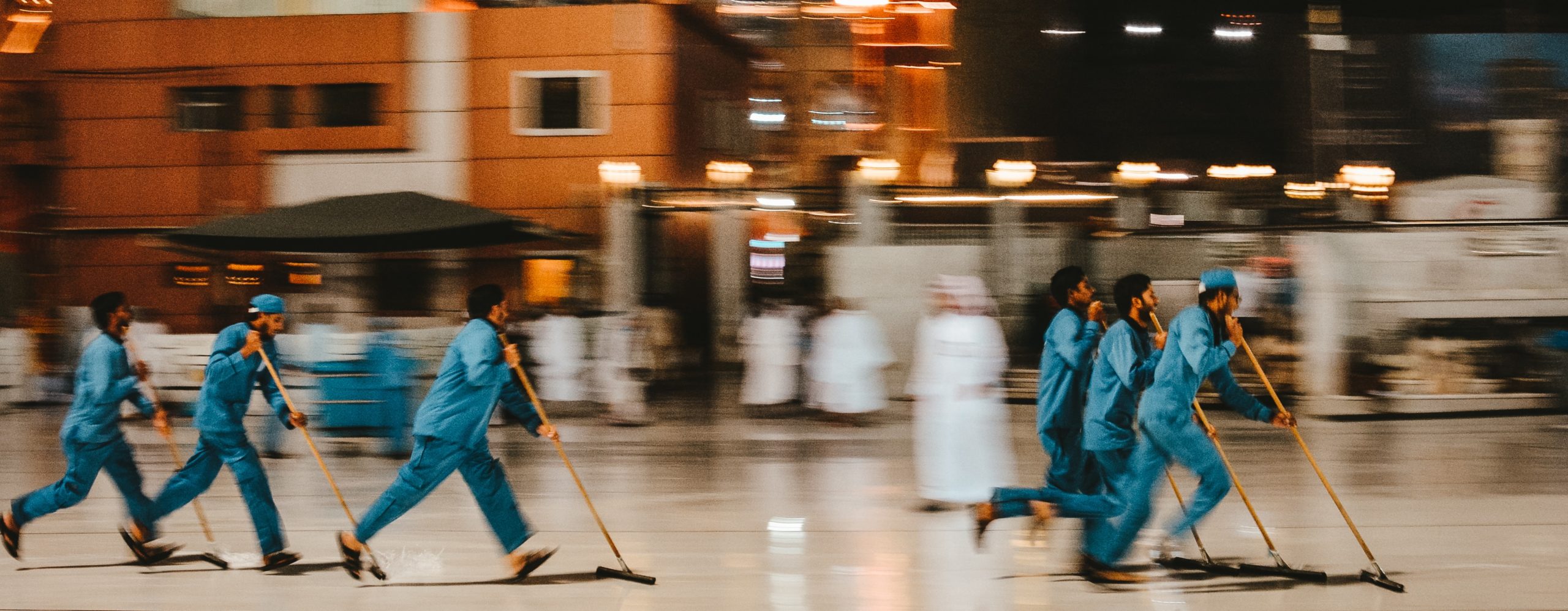 Workers in blue uniforms cleaning a floor.