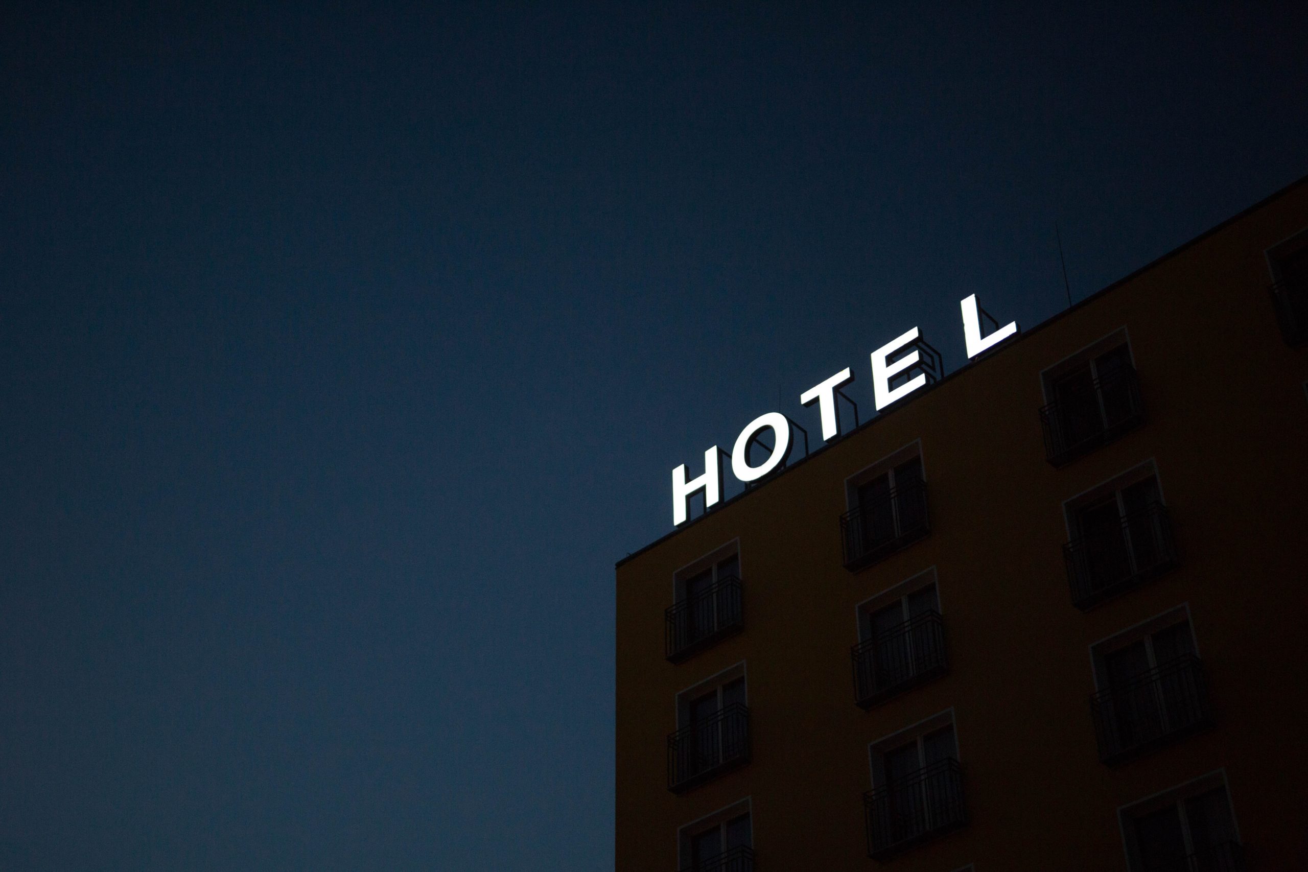 Hotel sign illuminated against dark evening sky.