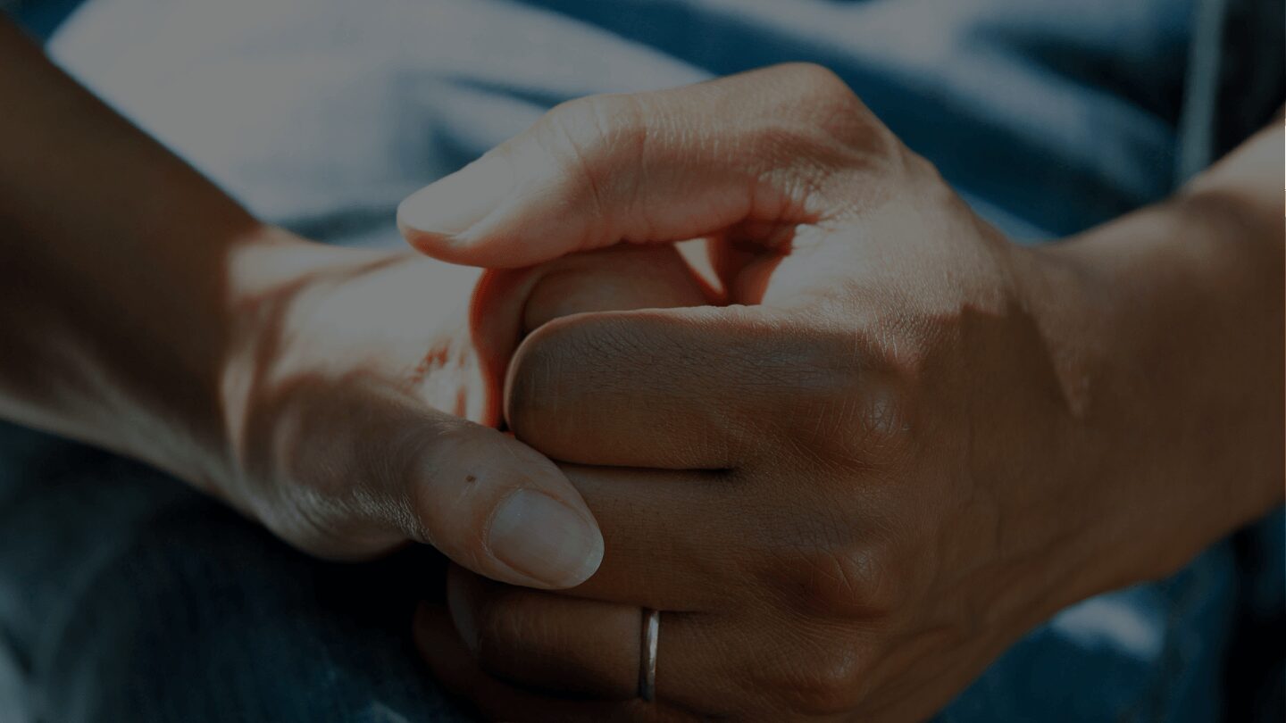 Hands clasped together with sunlight shadows.