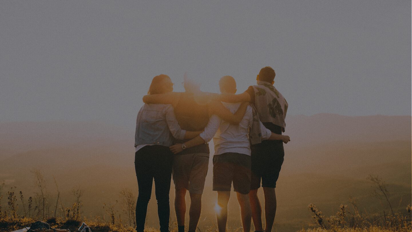Group of friends embracing at sunset.