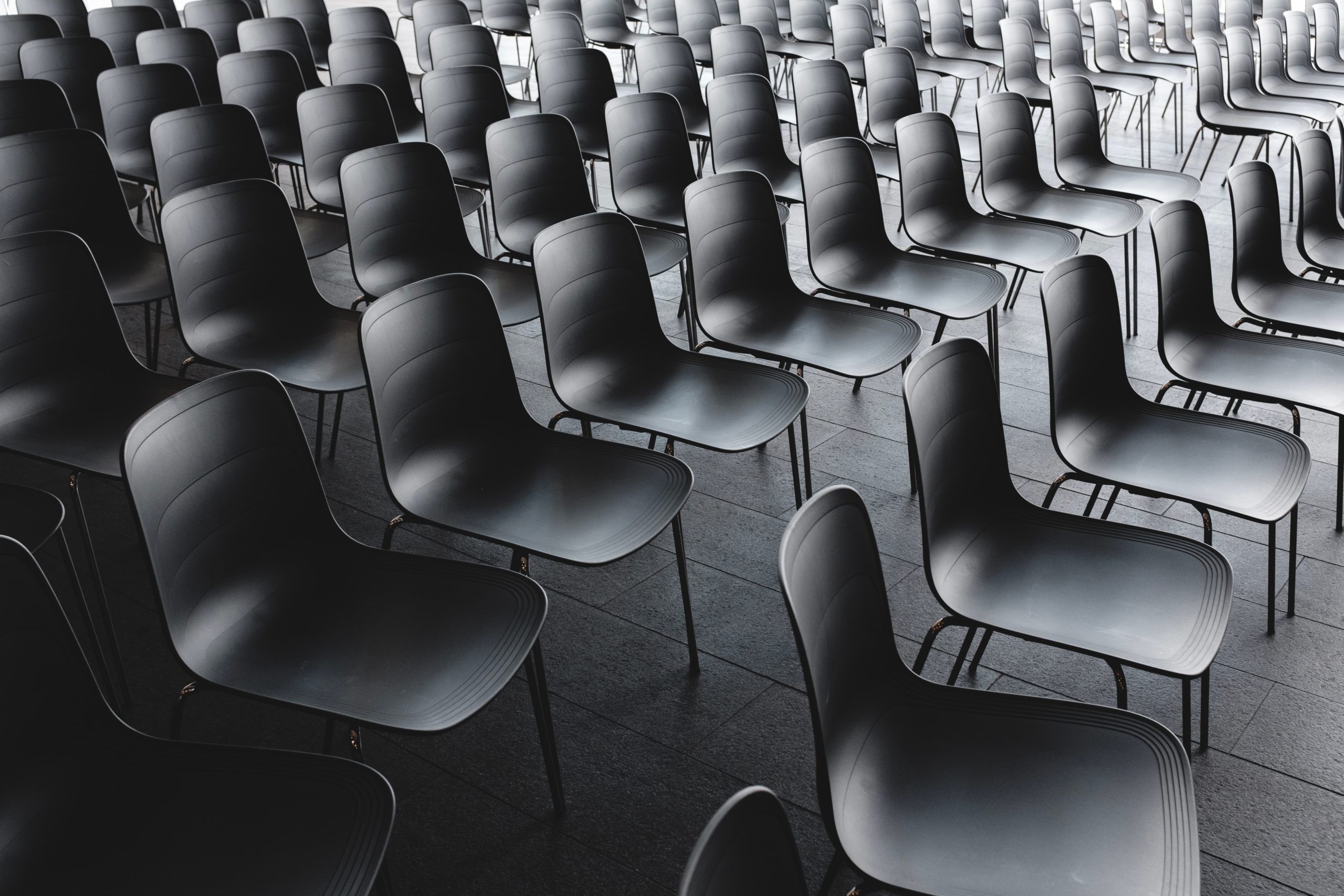 Rows of empty black chairs in auditorium.