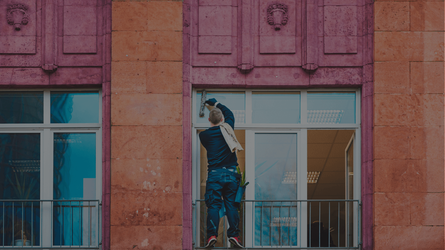 Person cleaning large window on building exterior.