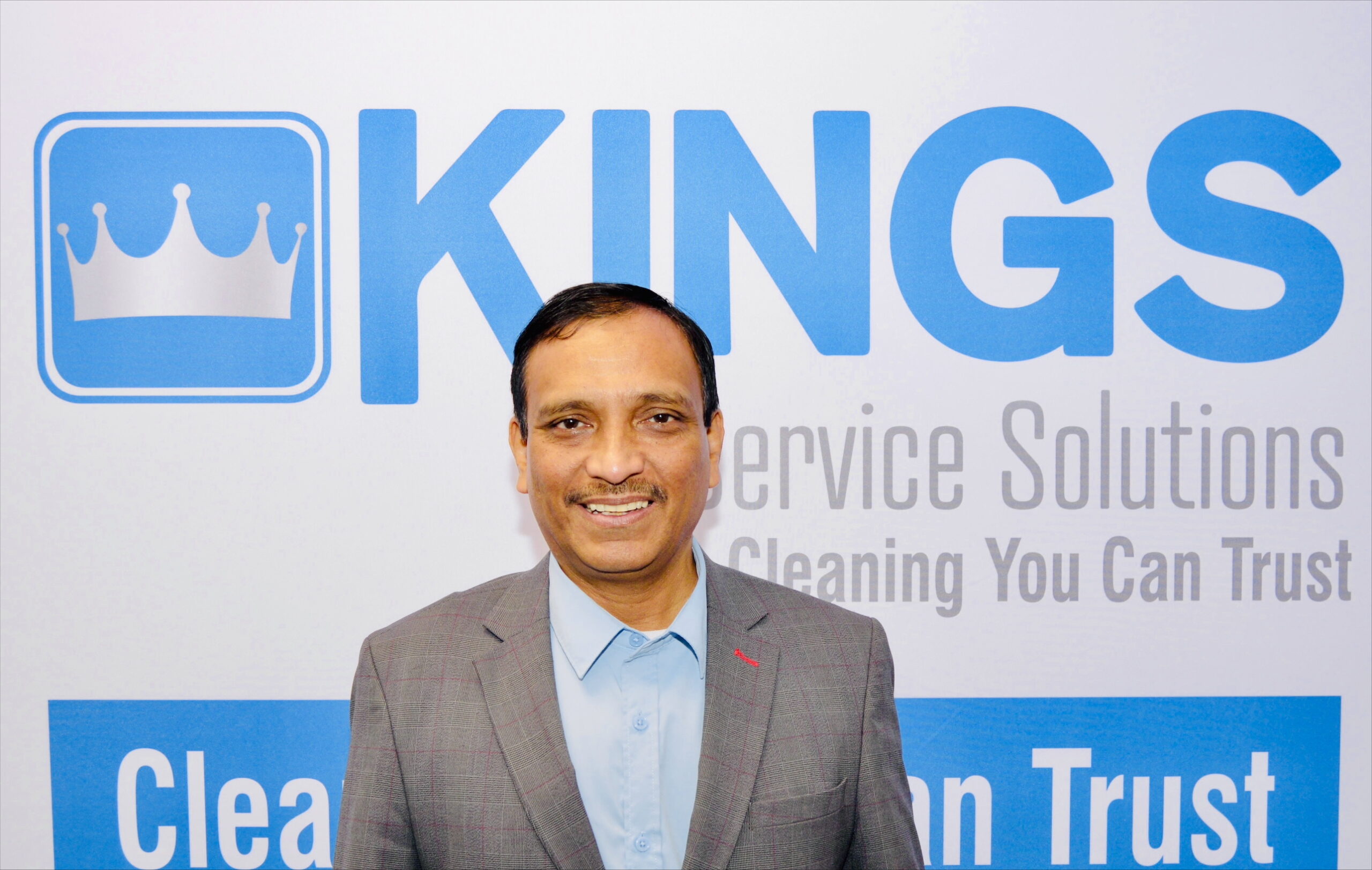 Man smiling in front of Kings logo.